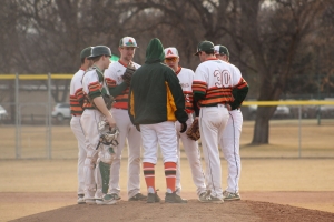 Photo of baseball participants congregating at the pitchers mound.